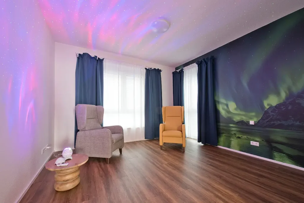 Ruhiger Aufenthaltsraum bei Pensum MED Gärtringen mit Deckenprojektor und Nordlicht-Wandmotiv.